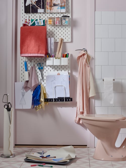 Bathroom with tiles, pegboards, containers, containers with lids, letter holders, hand towels, drawings, magazines, scissors.