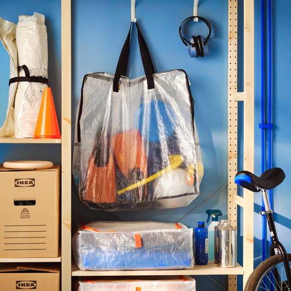 A wooden storage unit with a hanging DIMPA storage bag, a PÄRKLA storage case, and DUNDERGUBBE moving boxes.