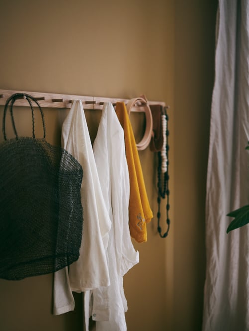 Clothes, a bag and various accessories in diverse colours hanging from a HÖVOLM hat and coat hanger.