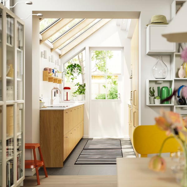 Una cocina con techo abuhardillado con ventanas y una puerta que da al patio, con armarios con frentes SINARP en chapa de roble.
