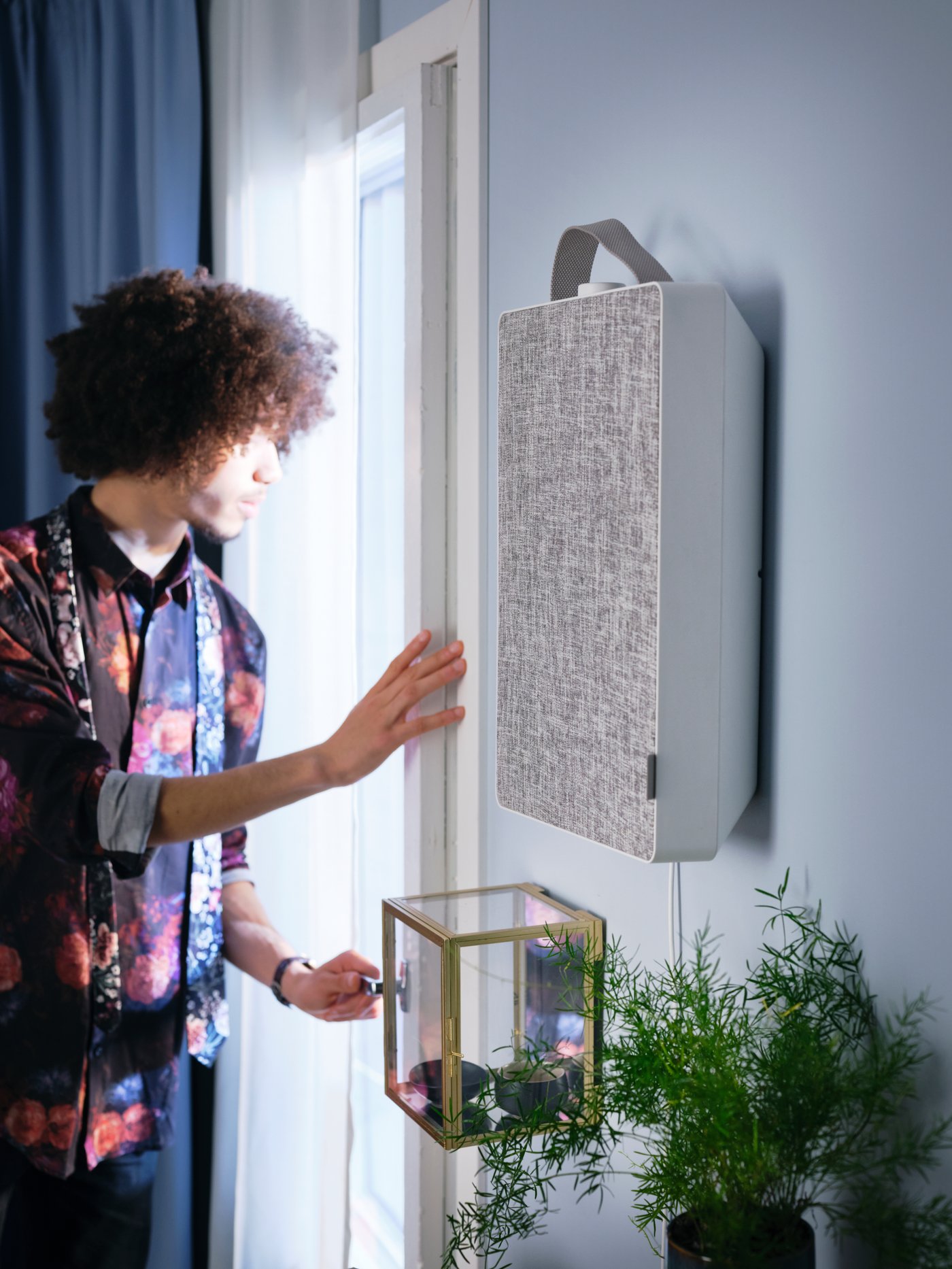 A man stands by a window and looks out while IKEA products are visible in the picture all around.