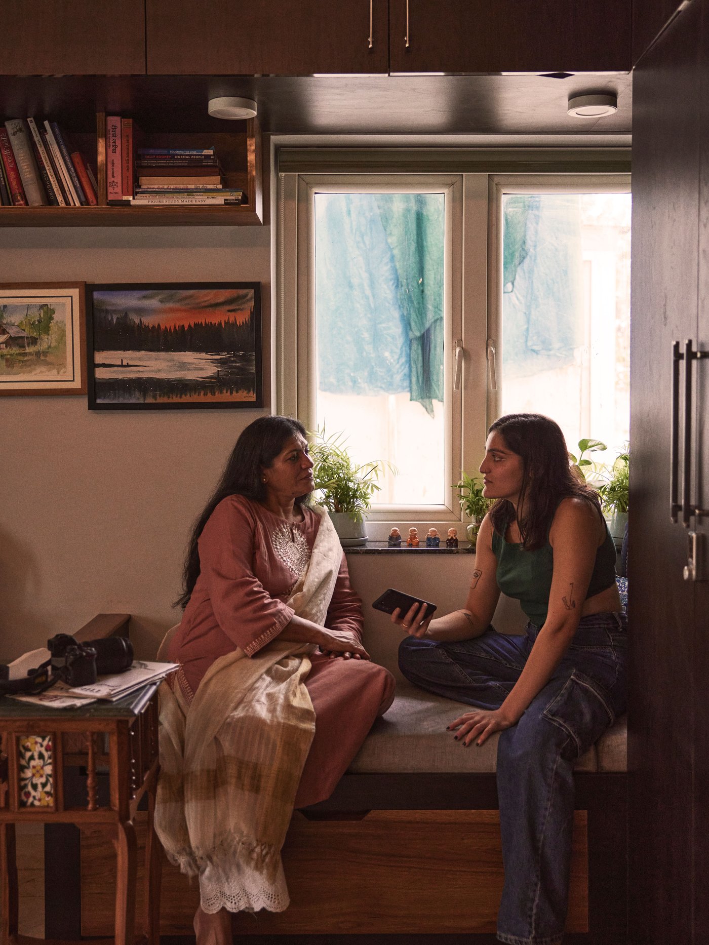 Two women sit on a sofa in a room next to each other and have a dialogue together.