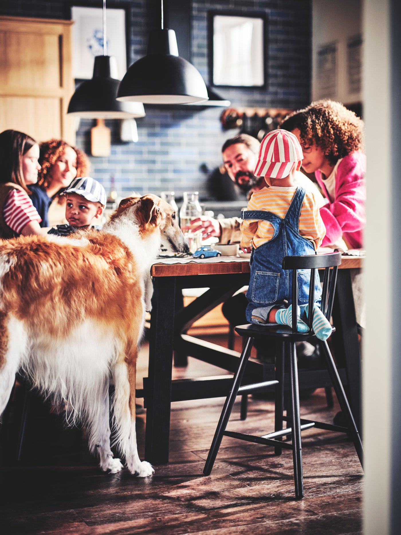 EIne Familie im Esszimmer an einem schwarzen SKOGSTA Esstisch. Das Kind sitzt auf einem AGAM Kinderstuhl.
