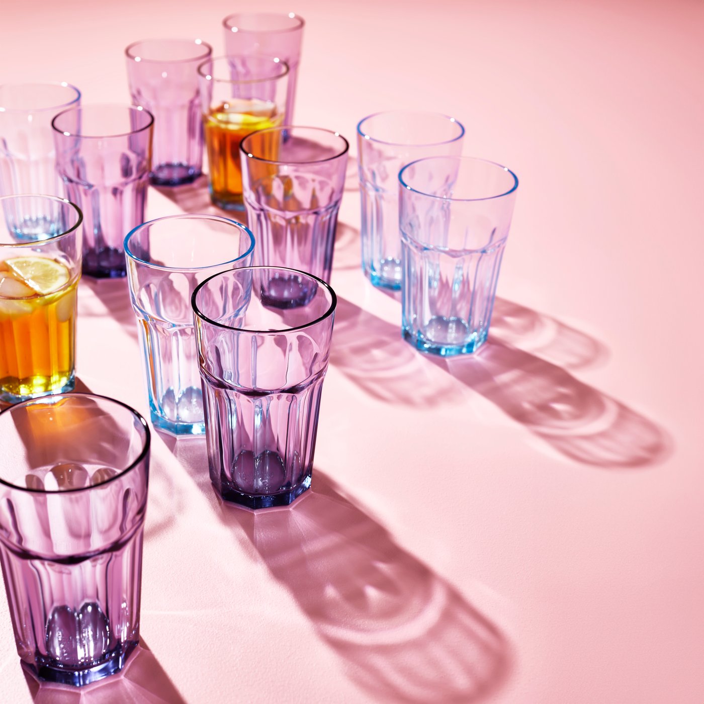 A bundle of light blue and purple POKAL glasses on a pink background.