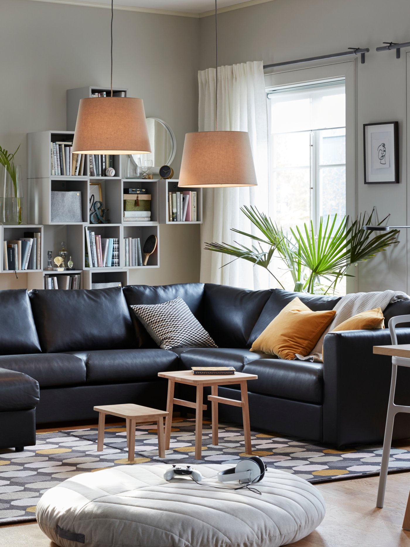 A living room with a black leather VIMLE corner sofa and two JÄRA pendant lamps hanging from the ceiling.
