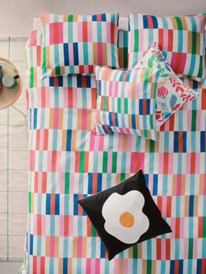 A couple of patterned cushions from the KLIBBKORSORT is flying through the air and landing on a bed, made with KLIBBKORSORT