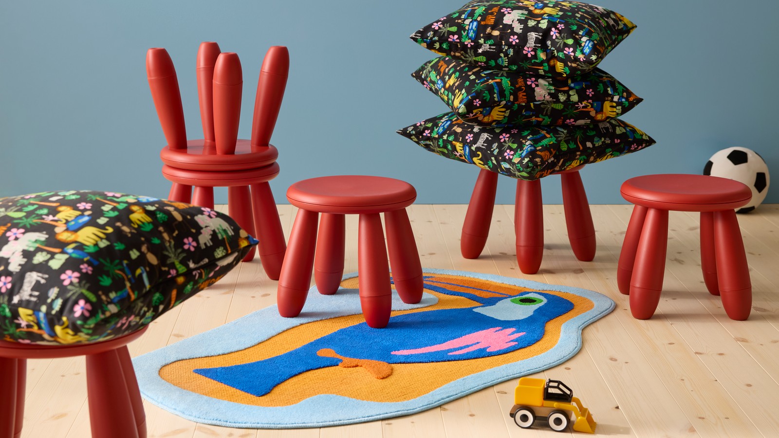 Šest crvenih dečjih stolica, jarko obojeni tepih sa tukanom i šareni jastuci sa temom džungle.