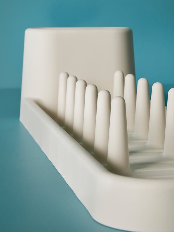 The STÄMLING dish drainer’s pegs in focus against a teal backdrop.