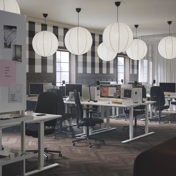 A focus zone in an office with sit/stand desks, SMÖRKULL office chairs, and GULLSUDARE pendant lampshades.