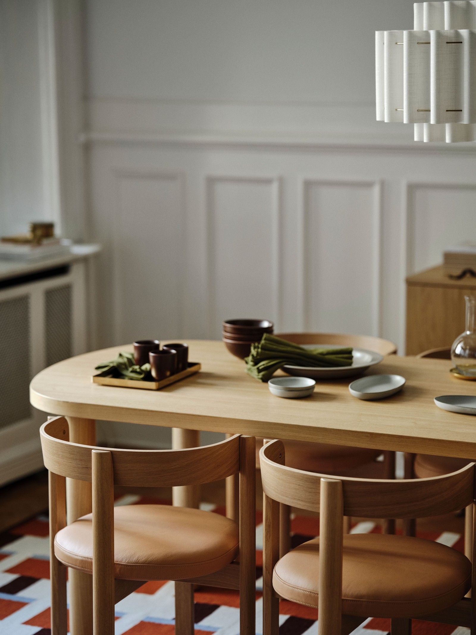 Four chairs around an oak veneer STOCKHOLM 2025 table with a carafe, bowls, napkins, serving plates, and other items on it.