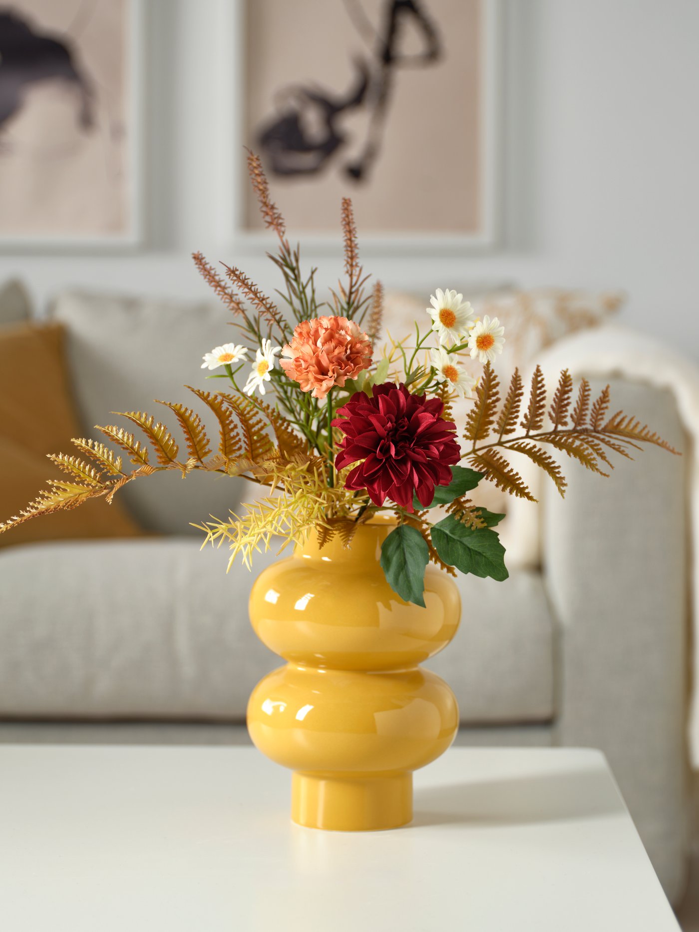 A multicolour SMYCKA artificial bouquet in a yellow vase on a coffee table in the living room.