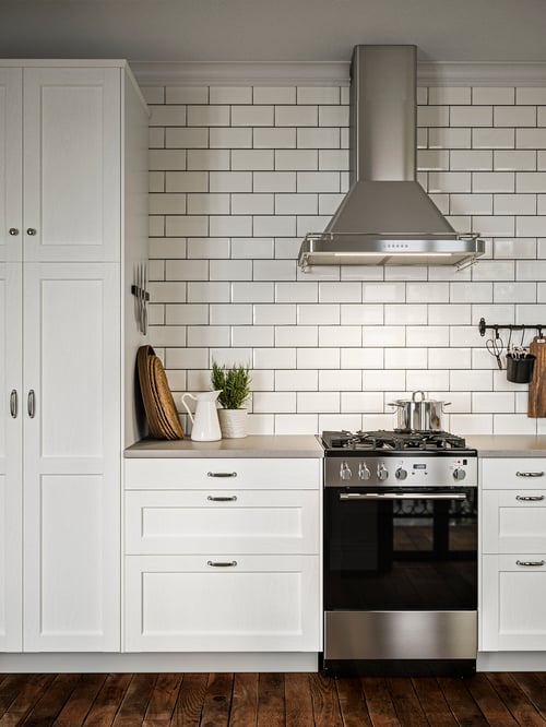 Kitchen with 2 base cabinets with 3 drawers made of wood, a range with gas cooktop and a wall mounted extractor hood.