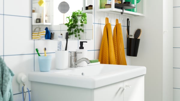 A close-up of a white bathroom vanity holding different bathroom accessories.