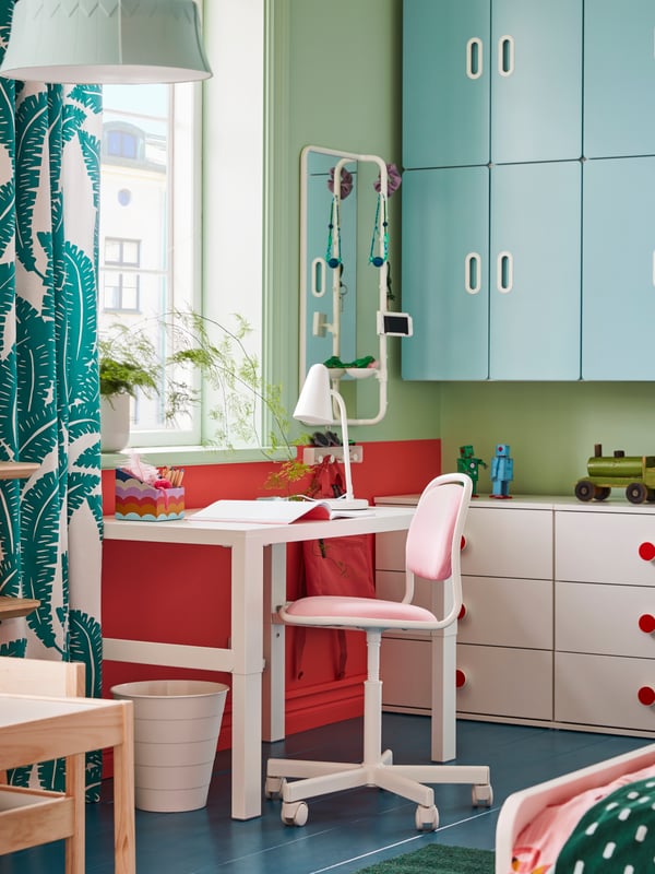 A children’s room with ample storage and a study space formed by a white PÅHL desk and a pink ÖRFJÄLL children’s desk chair.