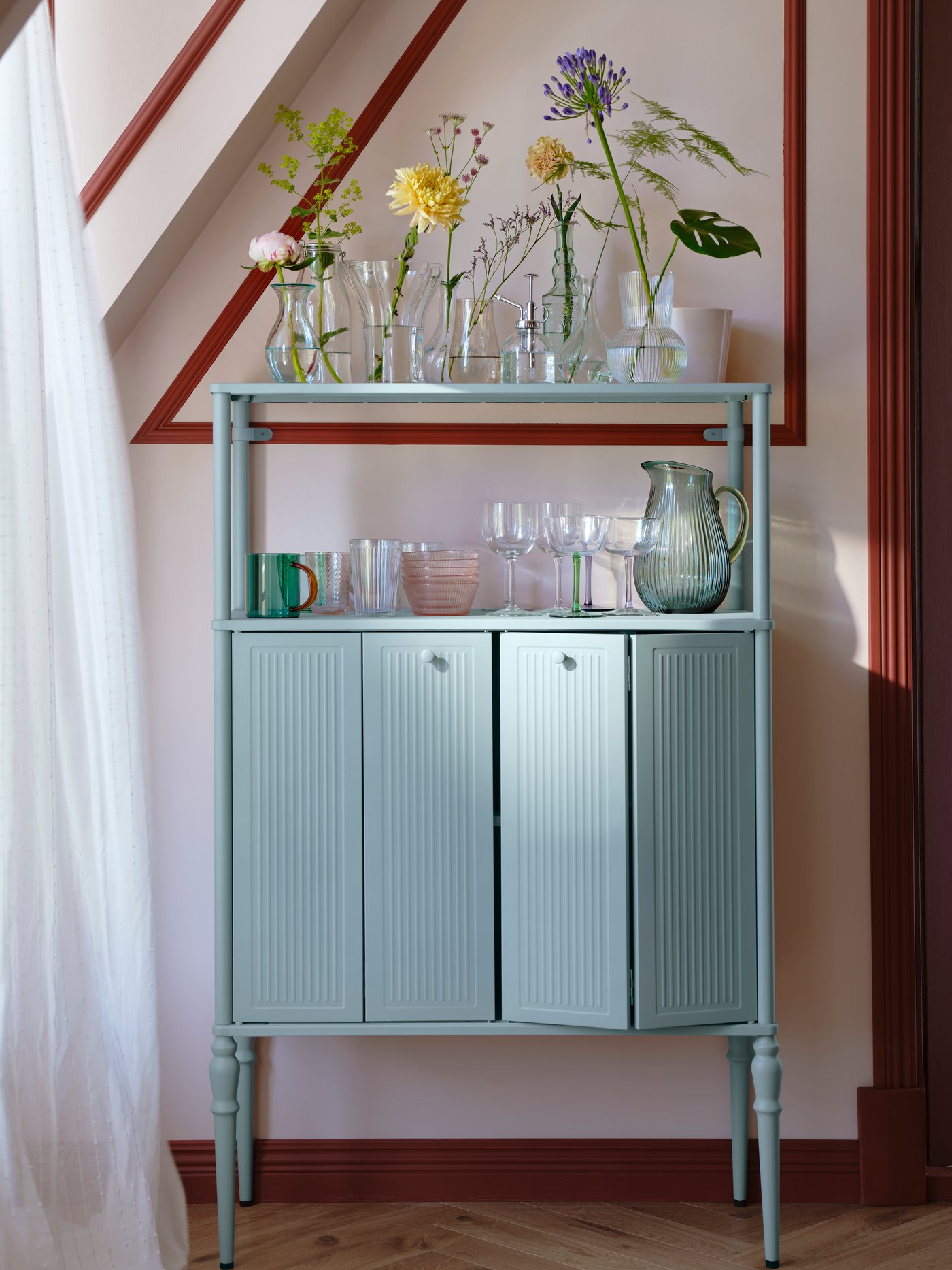 Szaroniebieska szafka SÅGMÄSTARE w jasnym pomieszczeniu ze skosami.