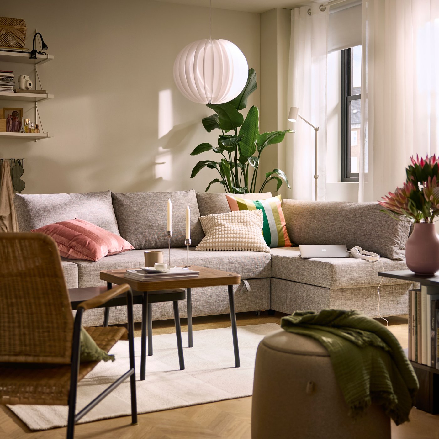 A light grey FRIHETEN corner sofa-bed with storage in a cosy living room featuring plants and decorative pillows.