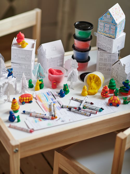 Ein Kindertisch, gefüllt mit Figuren aus MÅLA Stadtschablonen aus Karton und MÅLA Knetmasse.
