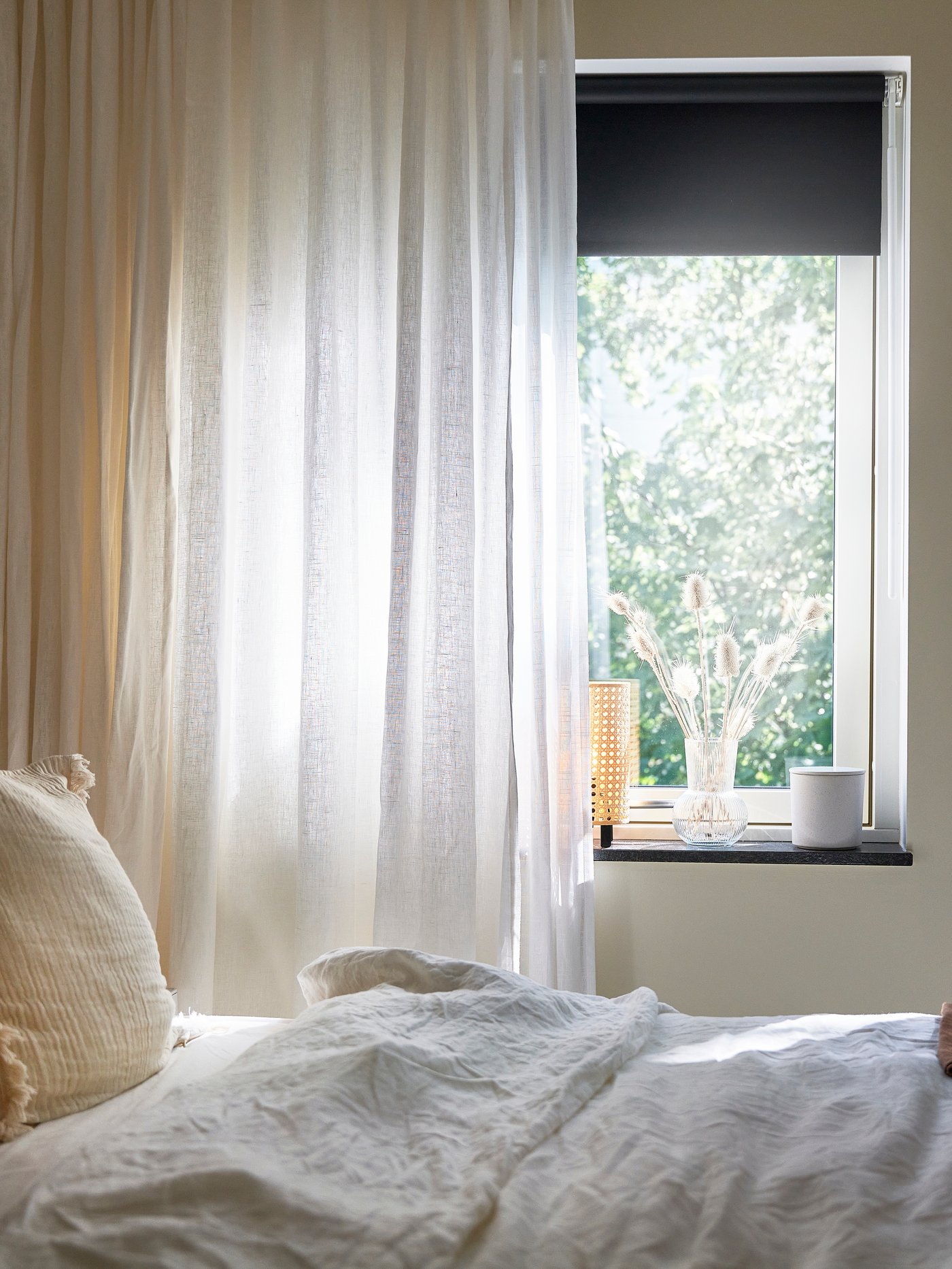 Närbild på gardiner som skymtas bakom sängen.