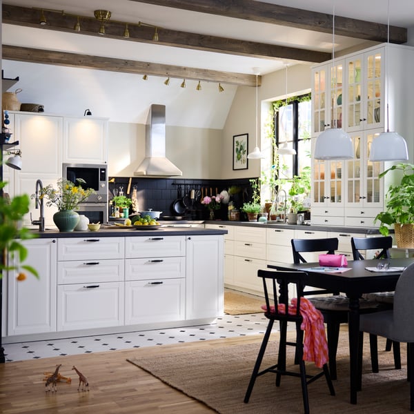 A large, traditional style kitchen with white BODBYN fronts including a kitchen island and a dining suite in dark wood.