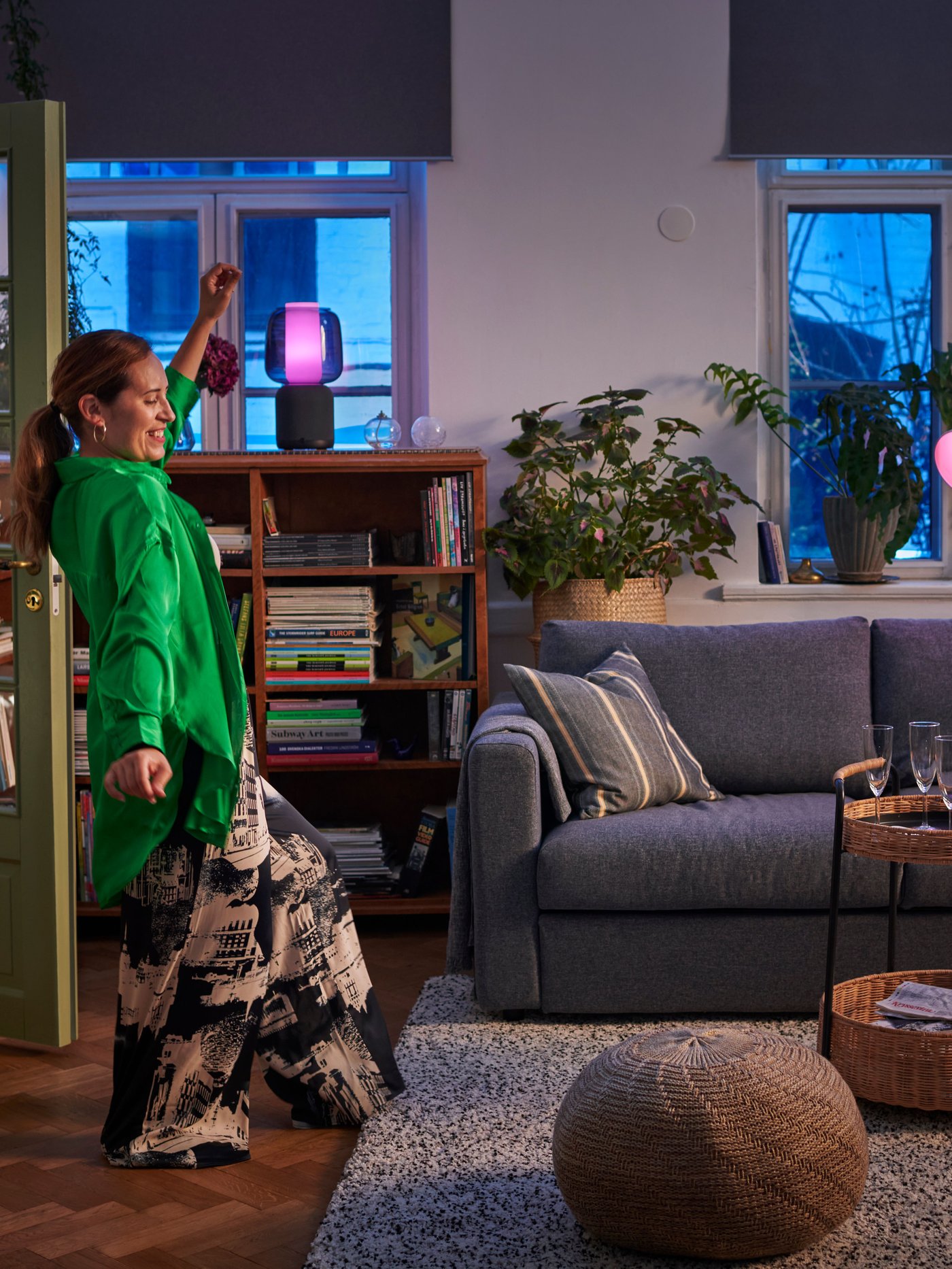 A woman wearing a green blouse is dancing in a living room with a VIMLE sofa and a VINDUM rug on a dark wooden floor.