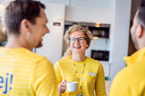 Three people chatting and laughing with a cup of coffee.