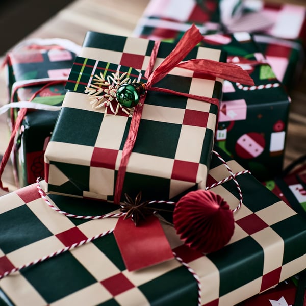 Julklapparna är festligt inslagna i VINTERFINT-presentpapper med ett djärvt grönt och rött rutmönster.
