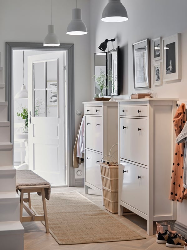 Long hallway with two shoe cabinets, hangers and a flatwoven jute rug.