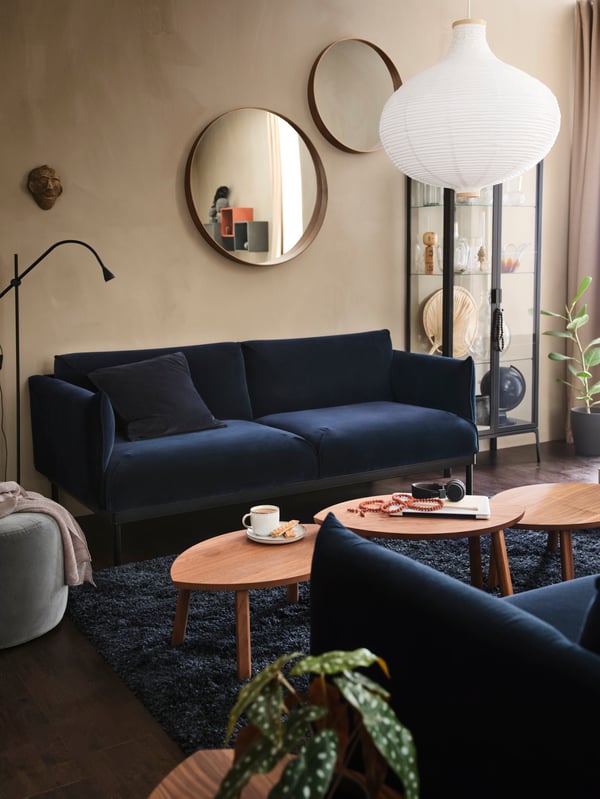 Two ÄPPLARYD sofas facing each other in a living room with a row of coffee tables between them with a cup and laptop on top.