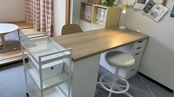 木目が特徴的なデスク、黄色い本棚等、淡い配色が印象的な部屋。