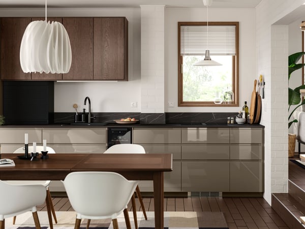 A dark kitchen has base cabinets with high-gloss dark grey-brown VOXTORP fronts and wall cabinets with brown SINARP fronts.