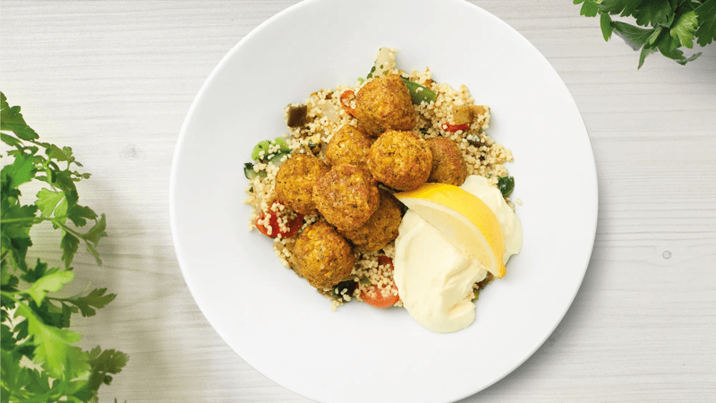 Falafelbällchen mit Couscous und Aioli Sauce in einem Teller angerichtet