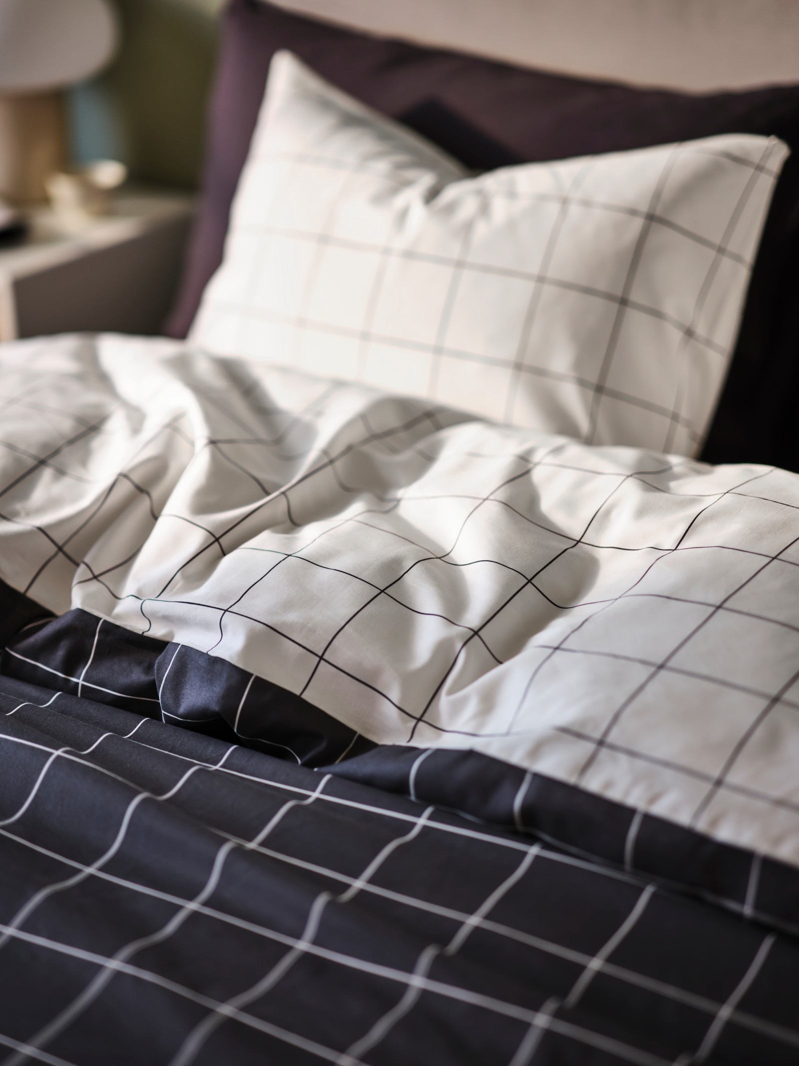 Jednostavna belo-siva karirana jorganska navlaka s odgovarajućim jastukom na krevetu u tradicionalnom deko stilu.