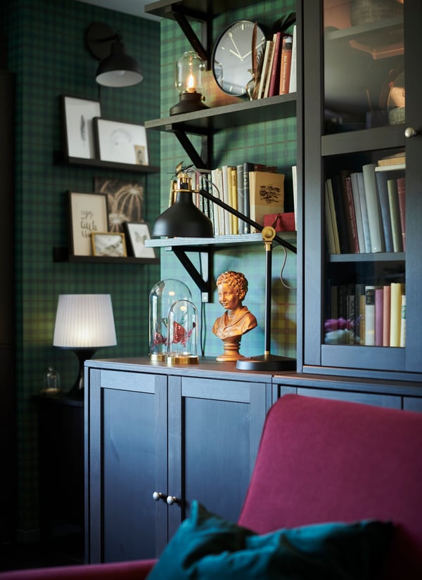 Front view of a cabinet on the wall above a desk and a SYMFONISK speaker. The image has a blue tone because of the VATTENSTEN LED lighting strip.