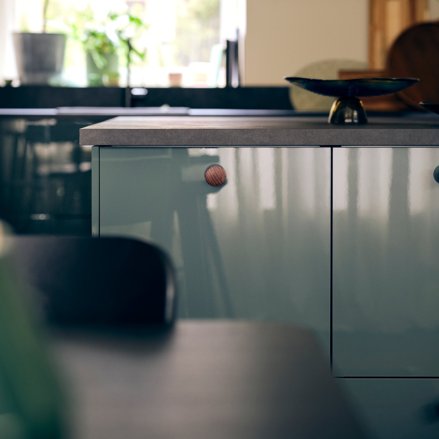 A kitchen with KALLARP high-gloss dark grey green kitchen fronts and an EKBECKEN worktop in black laminate with a bowl.