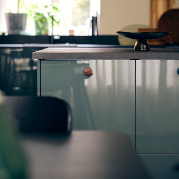 A kitchen with KALLARP high-gloss dark grey green kitchen fronts and an EKBACKEN worktop in black laminate with a bowl.