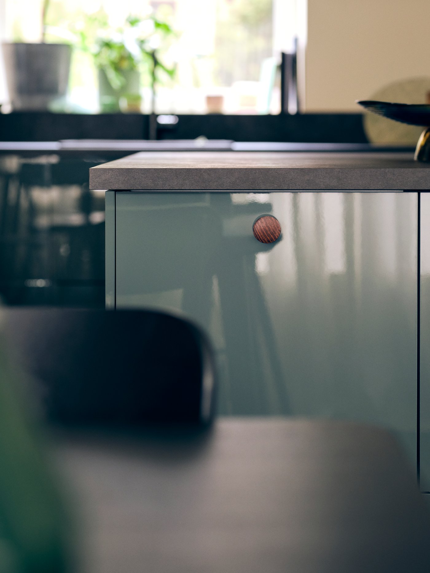 مطبخ بواجهات مطبخ KALLARP بلون رمادي أخضر غامق شديد اللمعان وسطح عمل EKBACKEN مصنوع من صفائح سوداء عليه سلطانية.