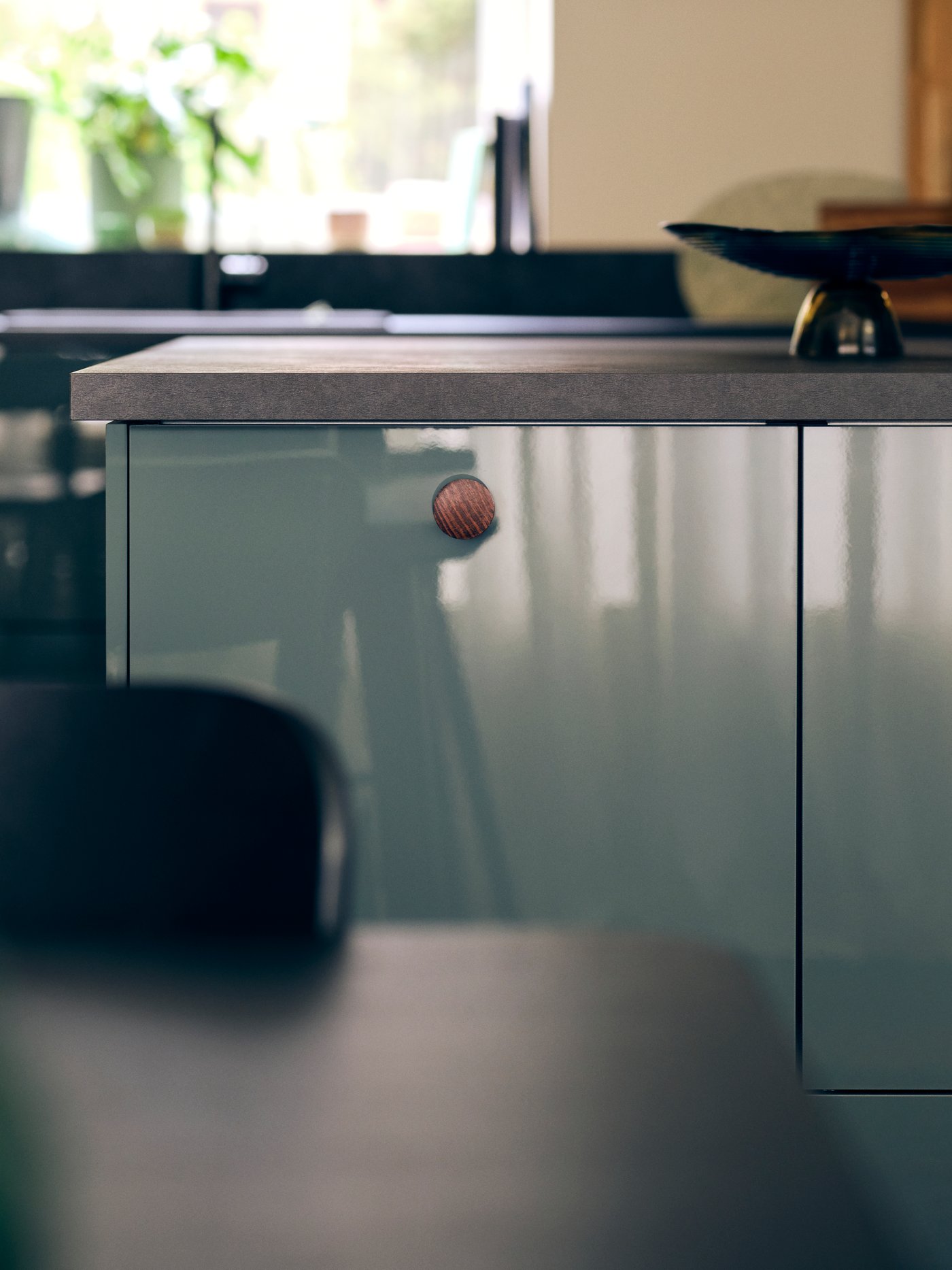 A kitchen with KALLARP high-gloss dark grey green kitchen fronts and an EKBACKEN worktop in black laminate with a bowl.
