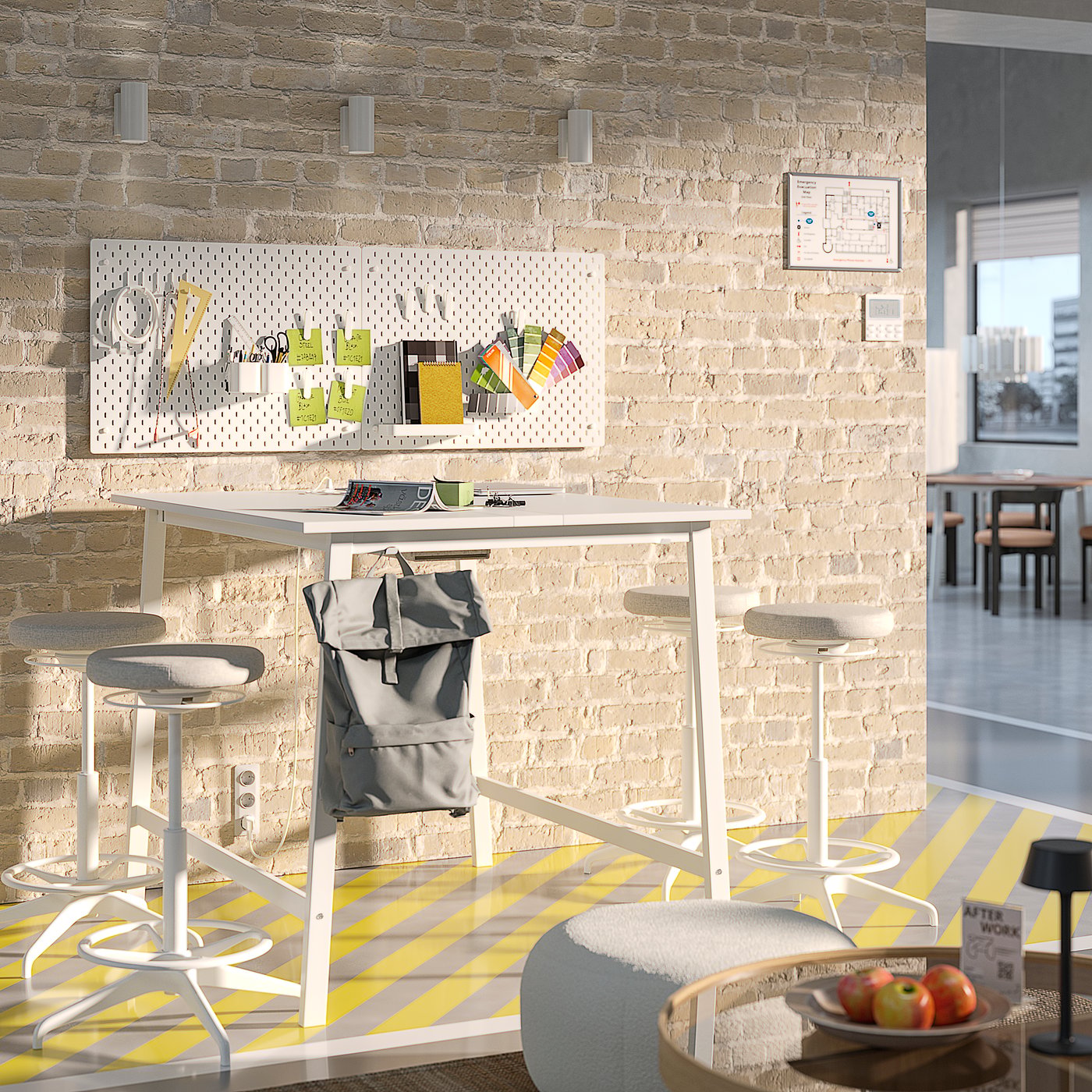 White standing table with four high stools, set against a lightbrick wall with pegboard containing art materials.