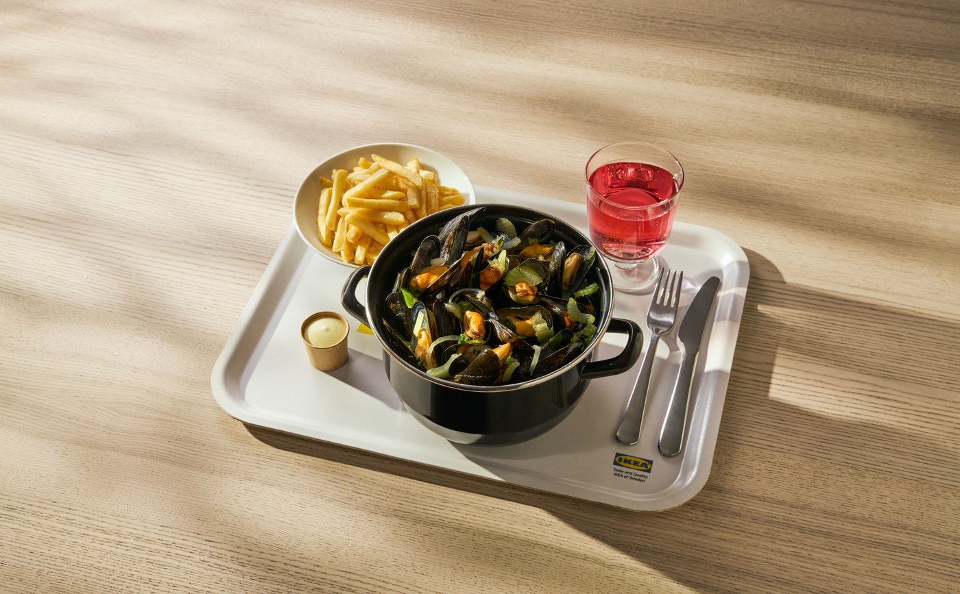 A steaming pot of mussels with vegetables, golden french fries, and a pink drink in an IKEA POKAL glass are served on a white IKEA tray, featuring an IKEA 365+ pot.