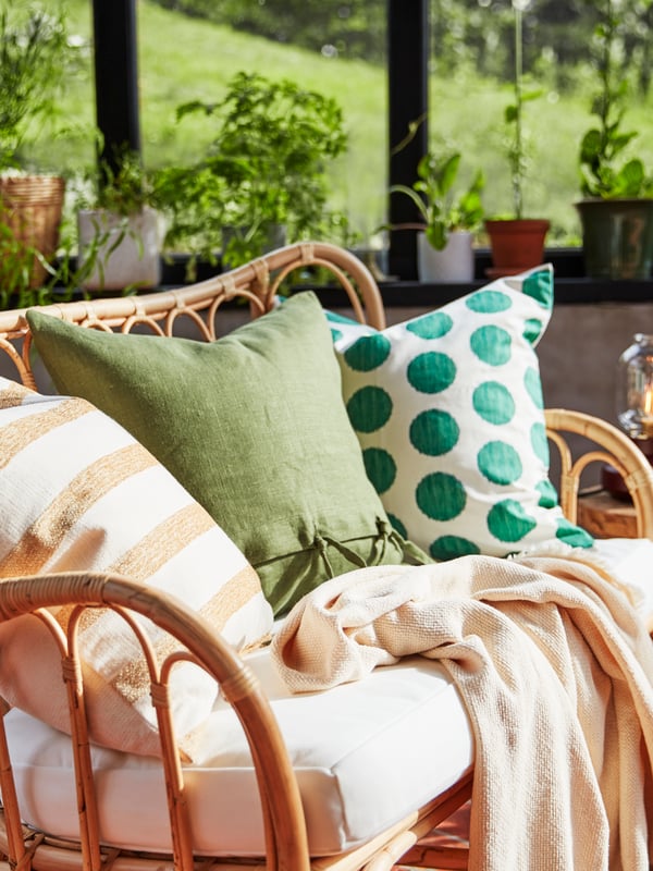A striped KNIPPARV cushion, a cushion in a green AINA cover and one in a dotted ÅSATILDA cover lie on a MASTHOLMEN sofa.