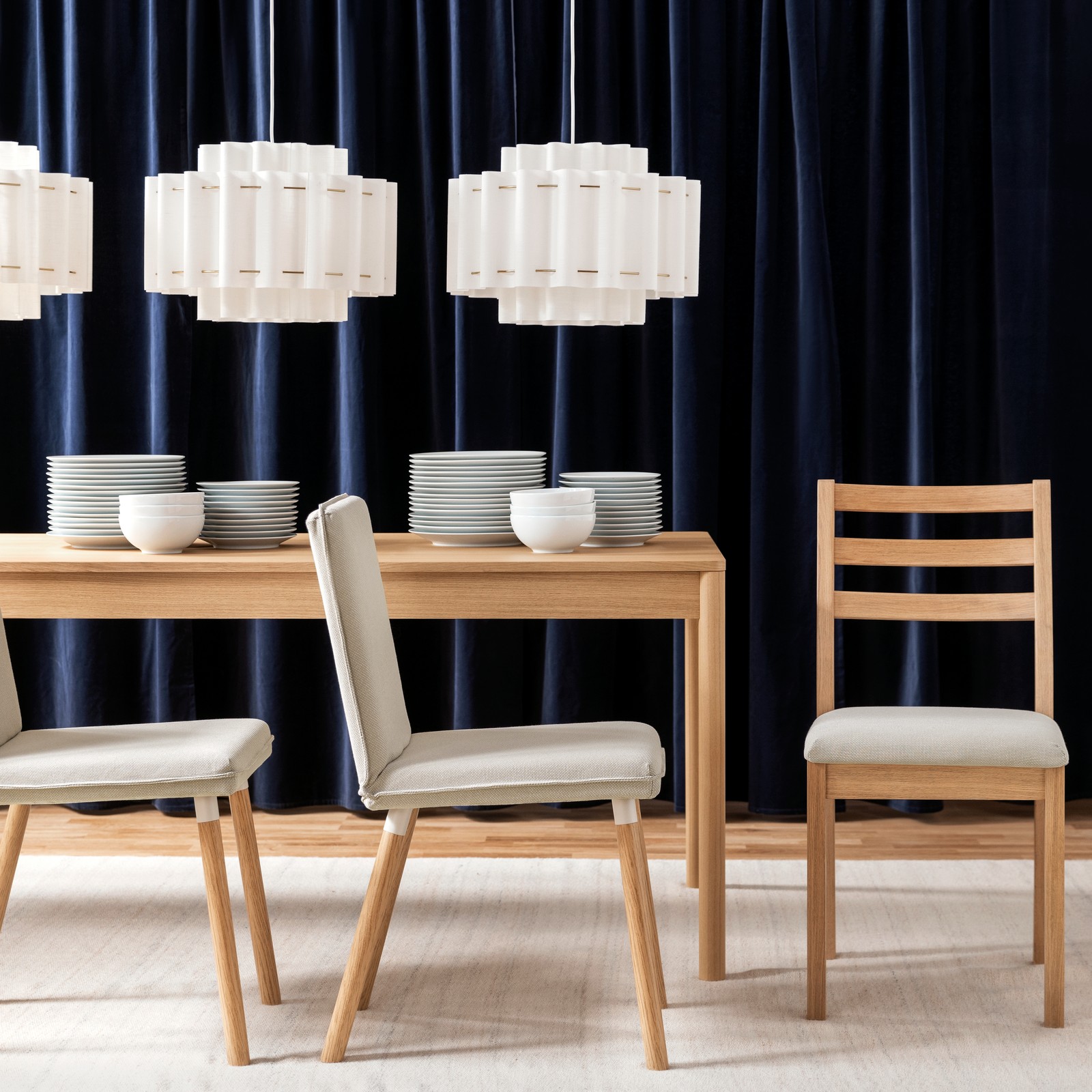 A bright dining space with a light wood TONSTAD chair beside a table set with plates and vases under stylish lamps.