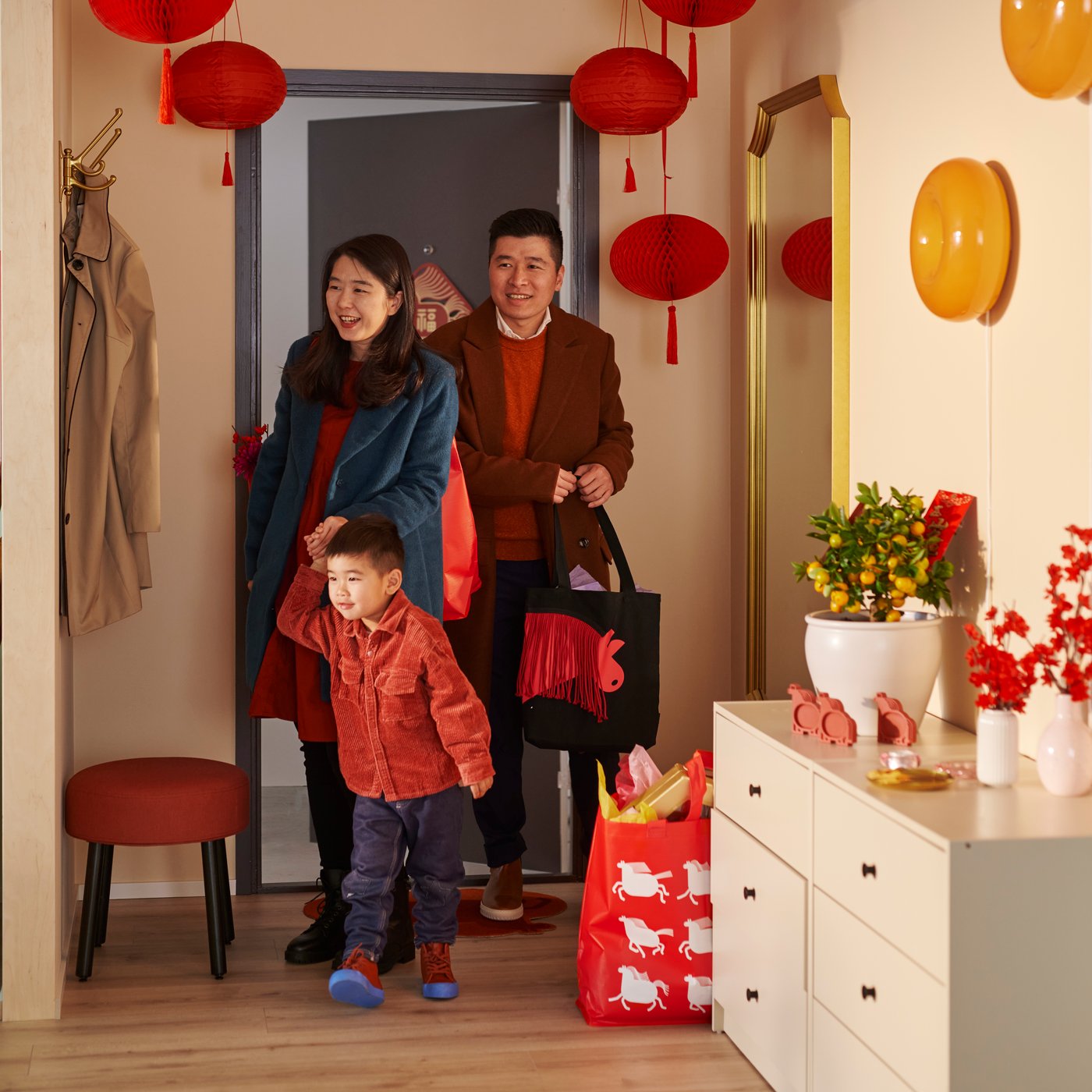 A warm entryway featuring FÖSSTA decorations and a FÖSSTA carrier bag welcomes a family as they step in through the door.