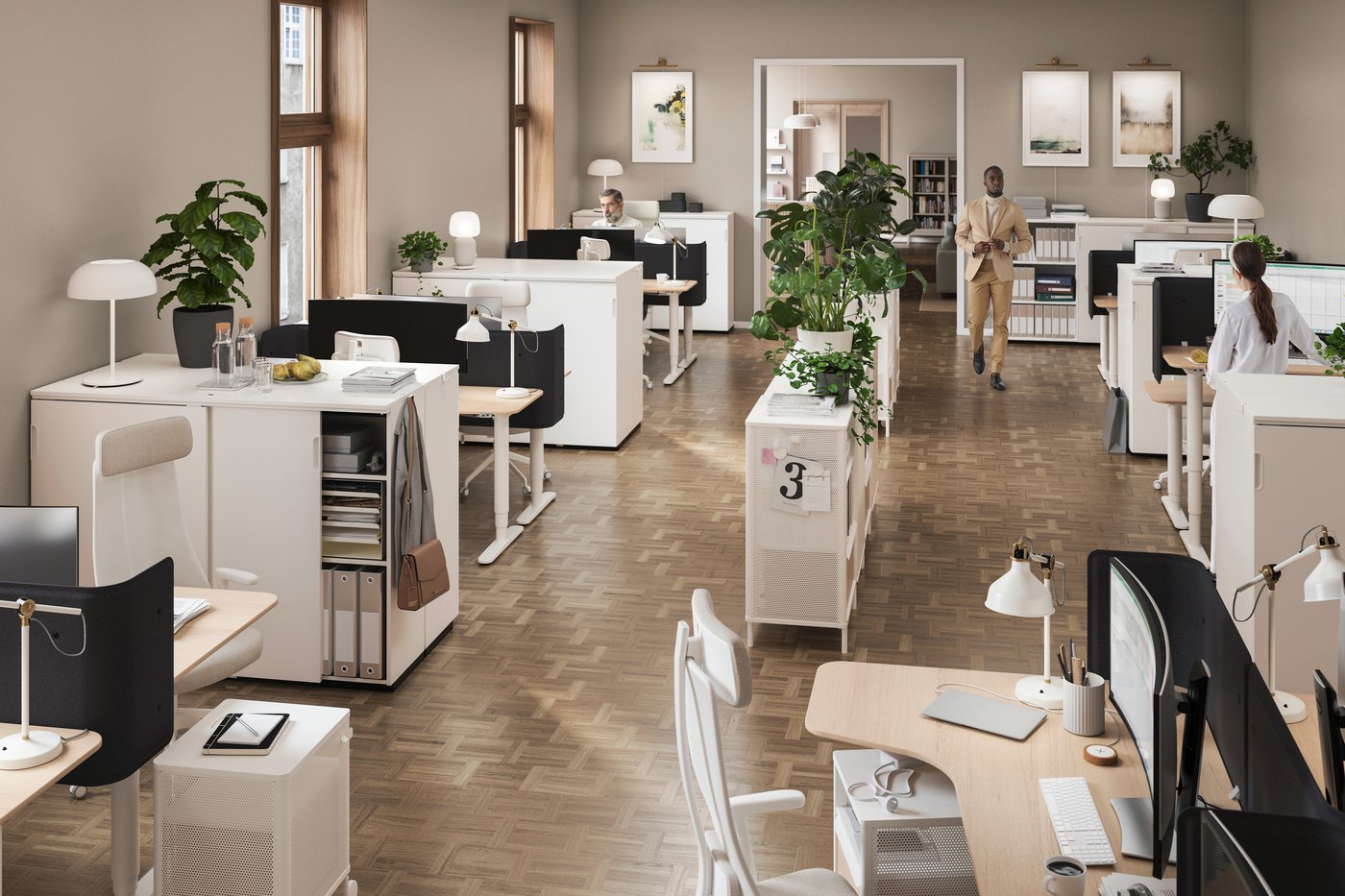 Oficina diàfana amb una prestatgeria central decorada amb plantes i centres de treball amb il·luminació al voltant, al costat de les parets.