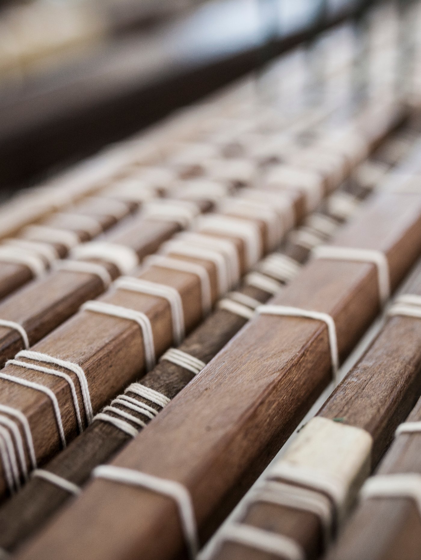 The wooden slats of a weaving loom threaded with white yarn.