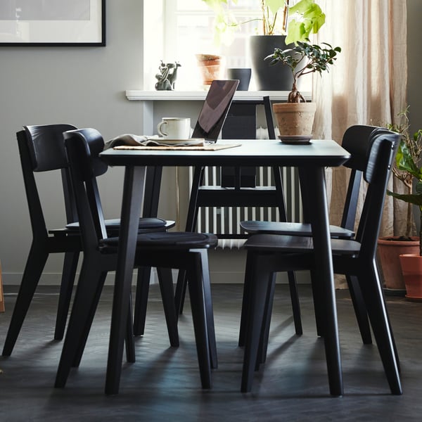 Un comedor con una mesa redonda y 4 sillas de comedor LISABO  negras.