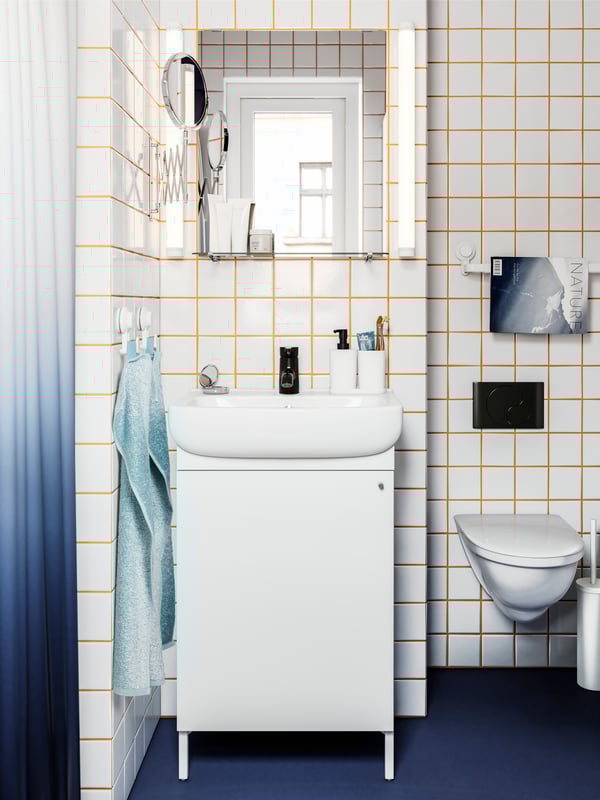 A bathroom with white tiles and orange grout lines featuring a NYSJÖN wash-basin cabinet and a NYSJÖN mirror with shelf.