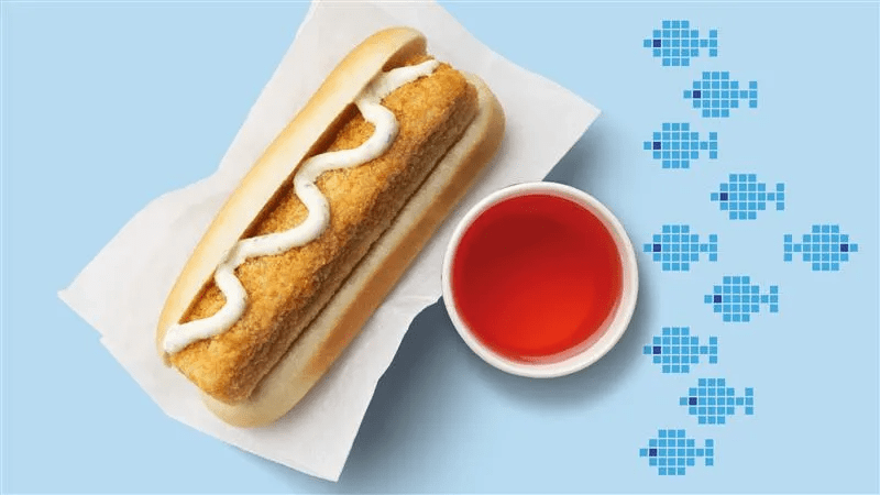 Fishhotdog mit einem Schwedenkracherl im Becher und blaue Fische im Hintergrund