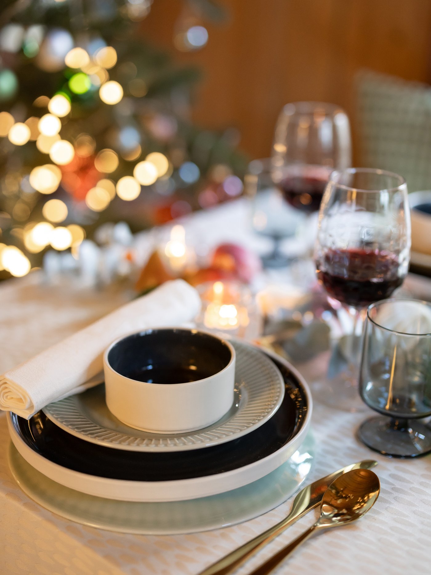 Auf einem festlichgedeckten Tisch befindet sich STRIMMIG und OMBONAD Essgeschirr und im Hintergrund sieht man verschwommen einen Christbaum