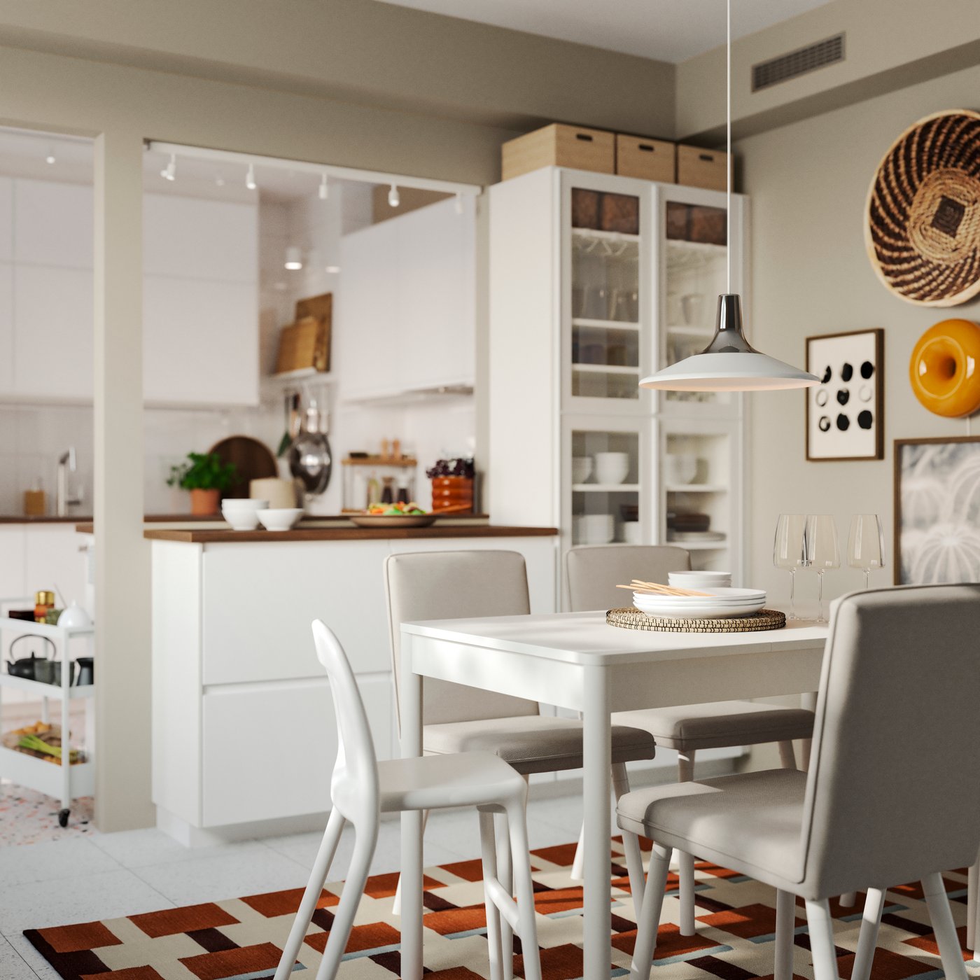 A white kitchen has a peninsula made of METOD kitchen cabinets and there’s a dining table and chairs in white.