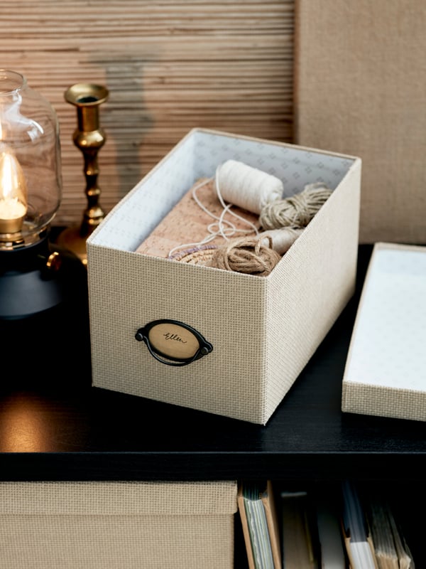 Caja beige KVARNVIK con lanas, hilos y agujas en su interior.